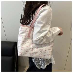 Detail view of pink leather strap and cute bow heart print on the cream tote bag