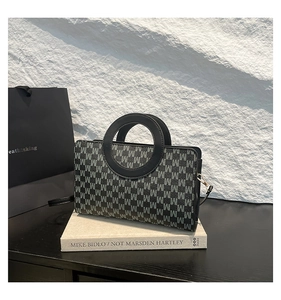 Détail d'un sac à main carré en jacquard avec motif M et des poignées rondes