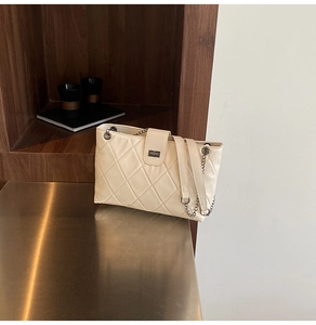Detailed view of the creamy white quilted bag with silver metal turn-lock and chain strap