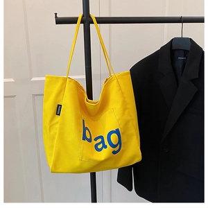 Detail view of yellow canvas tote bag with blue 'bag' print and sturdy fabric texture