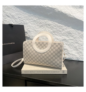 Détail du sac crème à motif M avec poignée circulaire évidée et bandoulière fine