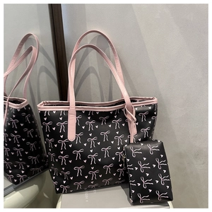 Detail of black tote bag with pink bow and heart patterns including matching small pouch