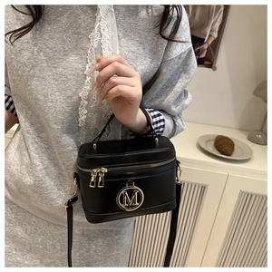 Détail d'un sac à main boîte noir avec grand logo M doré et fermeture éclair métallique