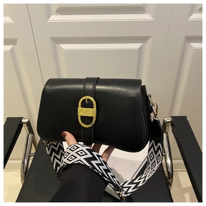 Close-up of black crossbody bag with gold buckle and woven geometric wide strap