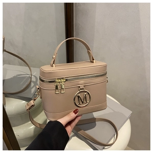 Detail of minimalist box handbag with metal M logo and elegant dual zipper closure