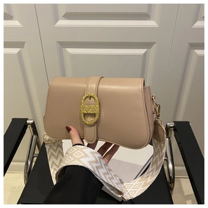 Detail of beige flap bag with gold oval buckle and patterned wide woven strap