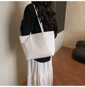 Detail view of woven texture on a white large tote bag carried by a model