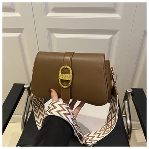 Close-up of a dark brown leather crossbody bag with golden horseshoe buckle and wide strap