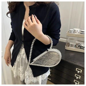 Detail of silver asymmetrical heart evening bag with large sparkling crystals on the handle