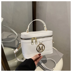Detail of white box handbag showing golden M metal logo and dual zipper closure