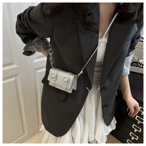 Close-up of a mini silver metallic crossbody bag with textured finish and chain strap
