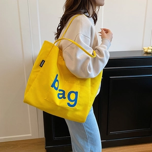 Large yellow canvas tote bag with artistic bag print and front pocket for daily commute