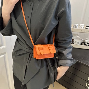 Mini bright orange square crossbody bag with dual buckle design on model for summer