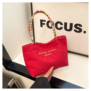Detail of red canvas tote with colorful beaded handle and golden fashion embroidery