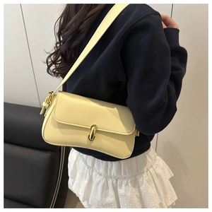 Detailed view of a creamy yellow leather shoulder bag with a gold metal twist-lock buckle