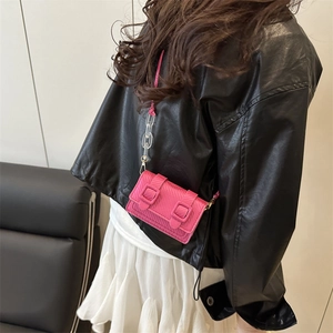Hot pink textured mini crossbody bag with square buckles and clear acrylic chain on model
