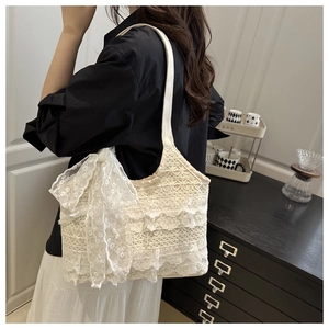 Detail of white lace shoulder tote bag featuring a large bow and elegant texture