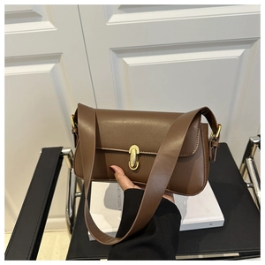 Detail of caramel leather underarm bag with gold oval twist lock and smooth texture