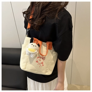 Dettaglio della borsa a tracolla in tela beige con cinturini arancioni e stampa di un orso