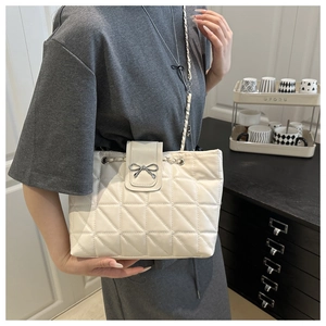 Detail of quilted leather bag with silver bow clasp and chain strap in daily setting