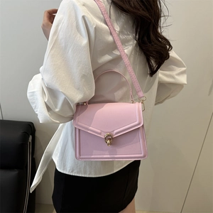 Minimalist pink square crossbody bag with gold twist lock and handle shown on model
