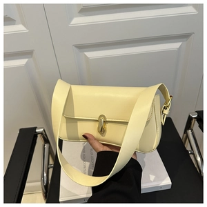 Detail of creamy yellow leather underarm bag with gold rotating metal clasp closure
