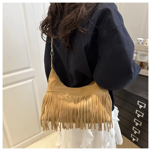 Detail of a brown suede crescent bag with fringe tassels and metal hook attachment