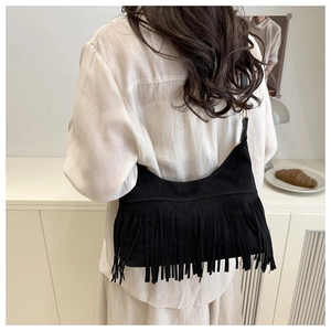 Detail of black suede crescent bag with long fringe tassels and boho shoulder strap