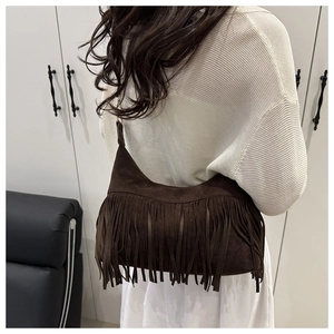 Detail of vintage brown suede tote bag with long bohemian tassels and shoulder strap