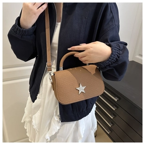 Detail view of brown woven handbag with silver star ornament and adjustable strap