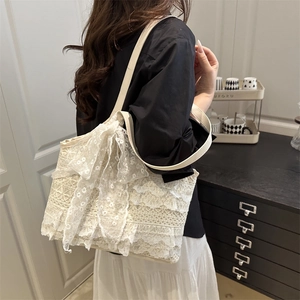 Elegant cream lace tote bag with a large bow and leather straps for casual luxury