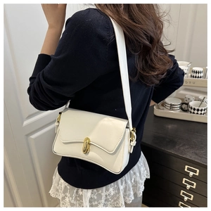 Detail of minimalist cream shoulder bag featuring a golden oval twist-lock closure