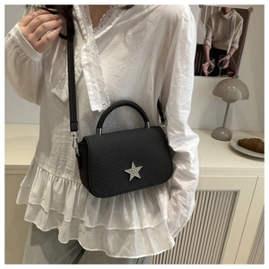 Detail of black saddle bag with textured fabric and sparkling silver star buckle