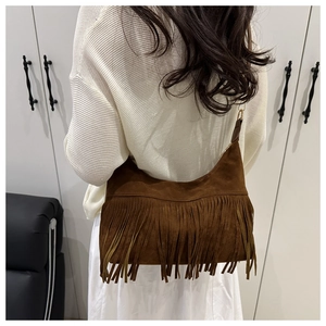 Close-up of brown suede hobo bag with long fringes shown on a shoulder