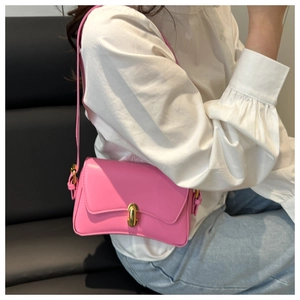 Close-up of bright pink shoulder bag with gold metal clasp and sleek curved bottom
