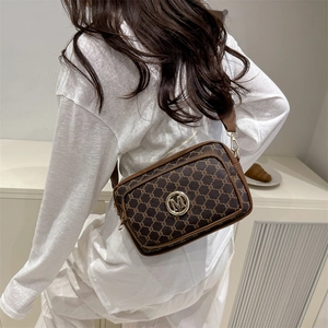 Sac bandoulière rétro marron à monogramme et logo M, porté par un mannequin en tenue blanche