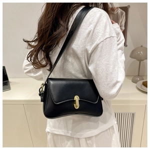 Detail view of a black leather underarm bag featuring a classic gold oval metal clasp