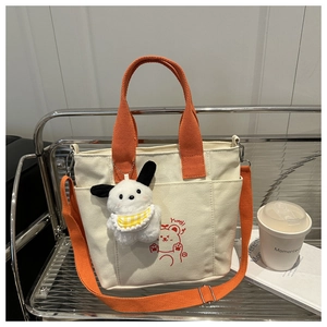 Dettaglio della borsa tote in tela beige con manici arancioni e stampa orsetto rosso