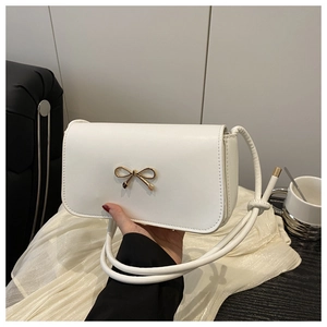 Detailed close-up of a white square handbag featuring a golden bow-knot metal clasp