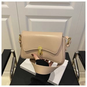 Close-up of nude faux leather shoulder bag with gold metal twist lock and wavy flap detail
