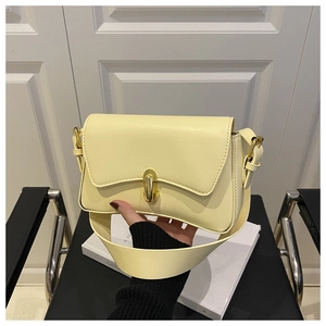 Detail of light yellow underarm bag featuring a golden oval twist lock and smooth leather