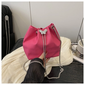 Detail of fuchsia crocodile texture bucket bag featuring a silver butterfly clasp and chain