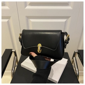 Detail of classic black baguette bag with elegant gold U-shaped buckle and leather strap