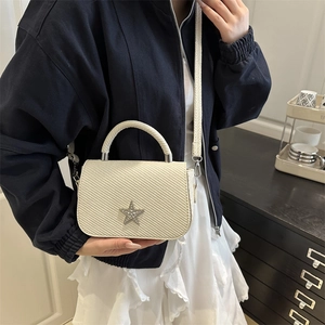 Borsa a sella trapuntata beige con logo a stella e tracolla indossata da modella