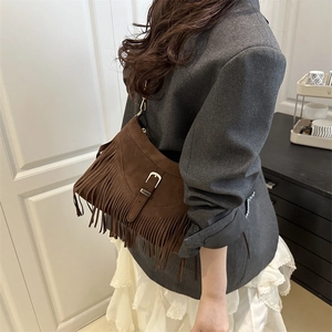 Sac fourre-tout en daim marron foncé avec franges et boucle argentée porté par un mannequin