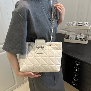 Chic quilted cream tote bag with metal bow buckle and chain strap shown on model
