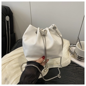 Detail of white crocodile pattern bucket bag with butterfly clasp and pearl drawstring