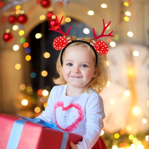 Close-up of Christmas reindeer antlers headband with red ears and Santa Claus ornaments