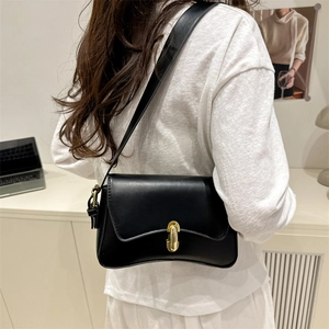 Minimalist black matte leather underarm bag with gold metal clasp shown on model