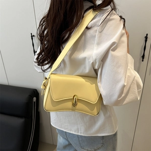 Minimalist light yellow underarm shoulder bag with gold metal clasp on a model